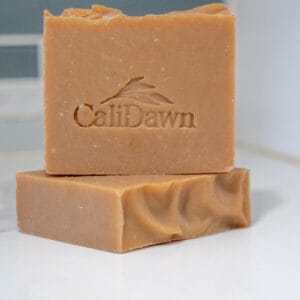 Two orange-rust colored soap bars stacked on a pedestal stand.