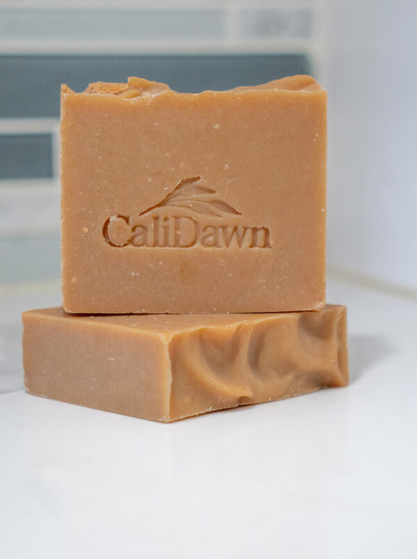 Two orange-rust colored soap bars stacked on a pedestal stand.