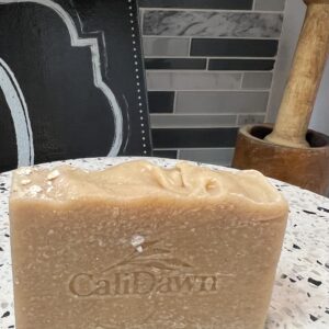 one bar of light brown soap with oats on top sitting on a pedestal stand