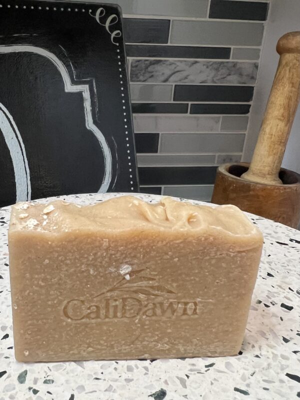 one bar of light brown soap with oats on top sitting on a pedestal stand
